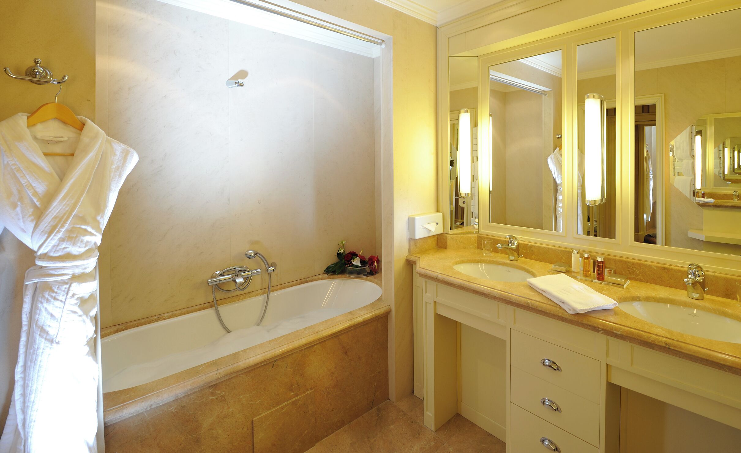 Un baño con bañera, un espejo grande y un tocador con lavabo.