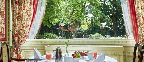 Una mesa preparada para el desayuno, con vistas a un jardín a través de una ventana.