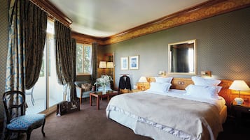 Une chambre d’hôtel avec un grand lit, un coin salon comprenant une chaise et une table, une commode et une fenêtre avec des rideaux.