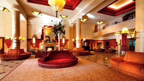 A spacious lobby with a central red seating area, multiple sofas, and a decorative plant arrangement.
