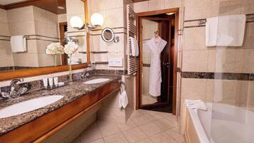 Een hotelbadkamer met twee wastafels, een grote spiegel, een handdoekrek en een bad.