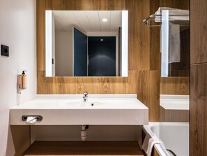 Une salle de bain moderne avec un grand lavabo blanc, un lambris en bois, un miroir et un porte-serviettes.
