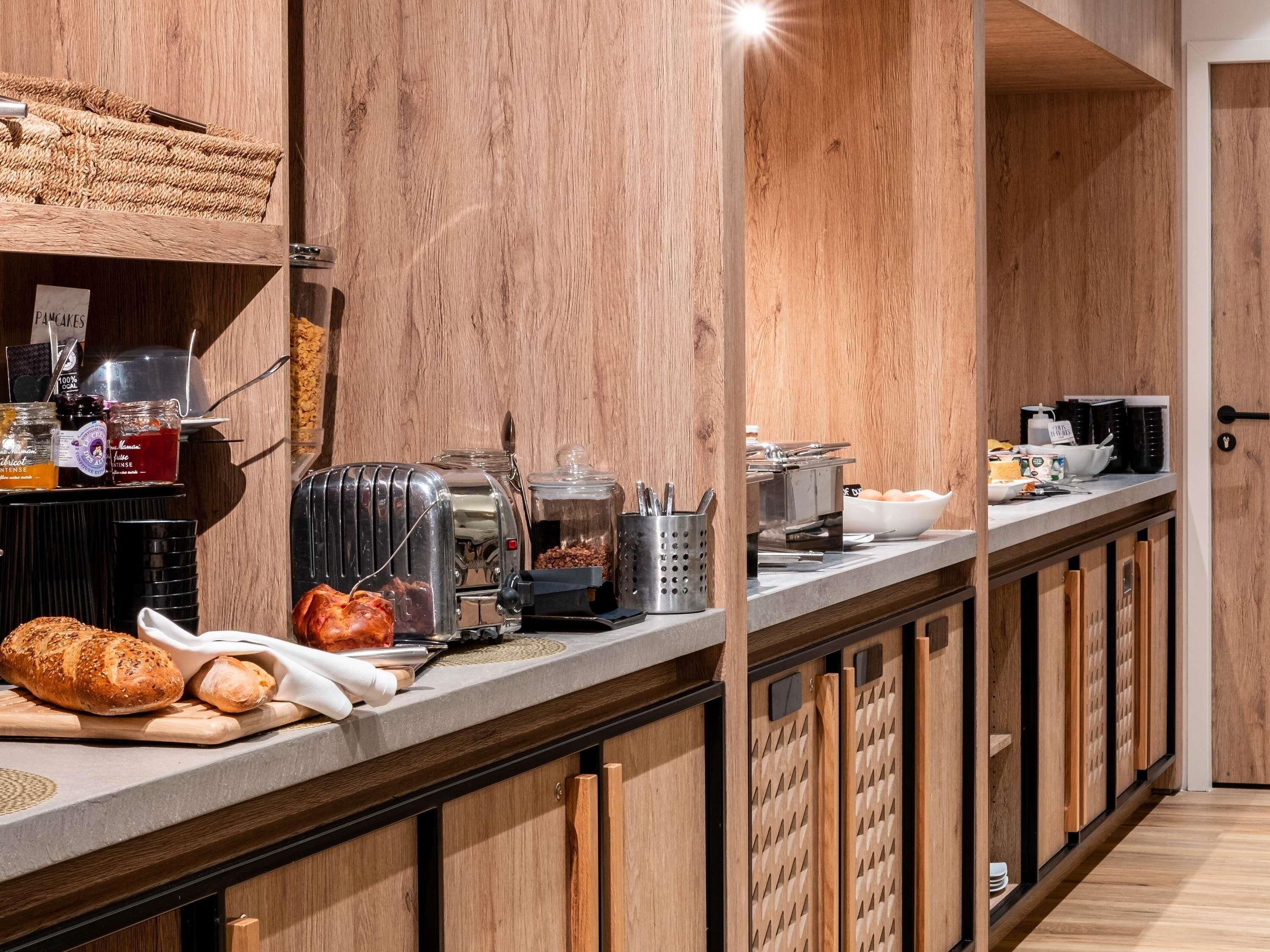 A modern kitchen with wooden cabinetry, a stainless steel toaster, and various kitchen utensils.