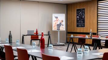 A conference room with tables, chairs, a projector screen, and a poster on the wall.