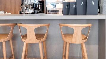 A bar area with wooden stools, a coffee machine, and black storage boxes.