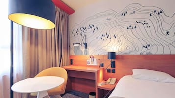 Ein Hotelzimmer mit einem Bett, einem Schreibtisch, einem Stuhl, einer Lampe und einer Wand mit einer topografischen Kartenlandschaft.