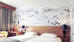 A hotel room with two beds, a wooden headboard, a desk, a chair, and a wall with a topographic map design. - Mercure Grenoble Centre Alpotel (Grenoble)