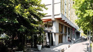 A modern building with large windows and a covered outdoor seating area. - Mercure Grenoble Centre Alpotel (Grenoble)