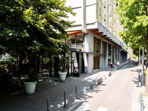 Un bâtiment moderne doté de grandes fenêtres et d’un espace extérieur aménagé avec des sièges.