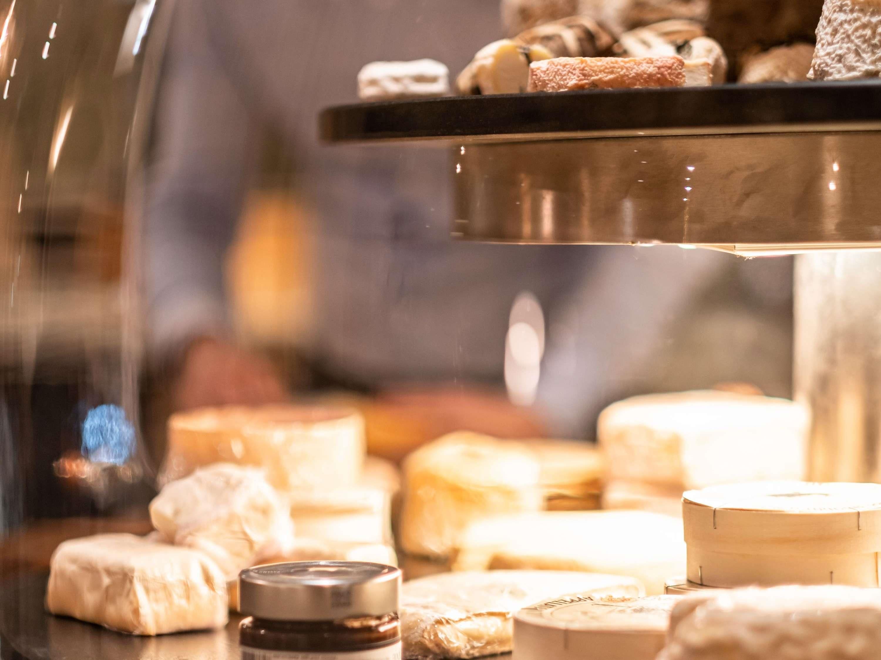 A variety of cheeses and pastries displayed in a glass case, likely in a food shop or deli.