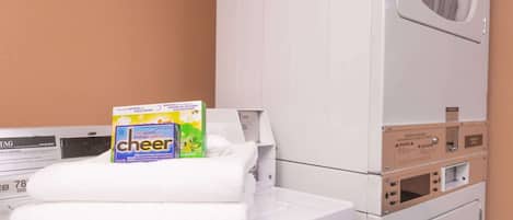 A laundry area with a washing machine, dryer, and stacked towels.
