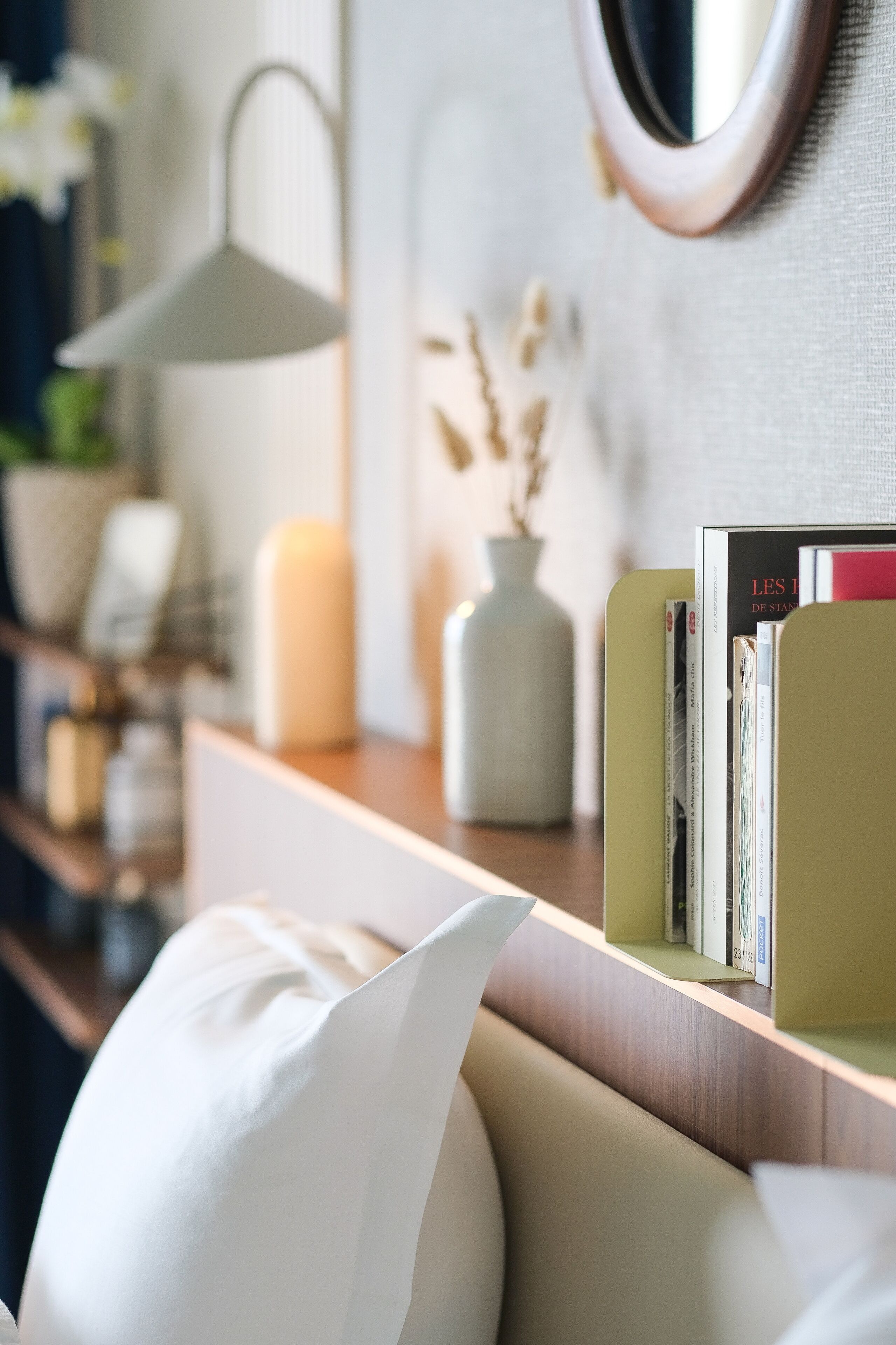 A modern living room with a sofa, a bookshelf, a lamp, and decorative items.