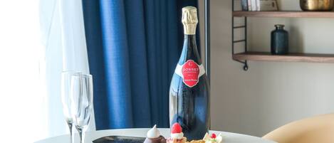 A bottle of Gosset champagne, two glasses, and a dessert tray on a round table.