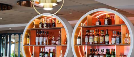 Zona de bar con estantes circulares que exhiben varias botellas de licor.