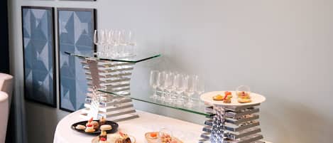 A buffet table with various desserts and a glass display case with wine glasses.