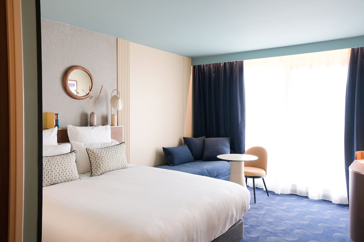 Habitación de hotel con una cama grande, un sofá, una mesita y una silla.