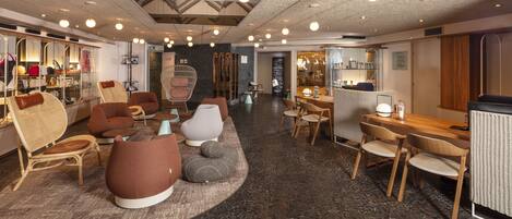 A modern lounge area with seating, a dining area, and a reception desk.
