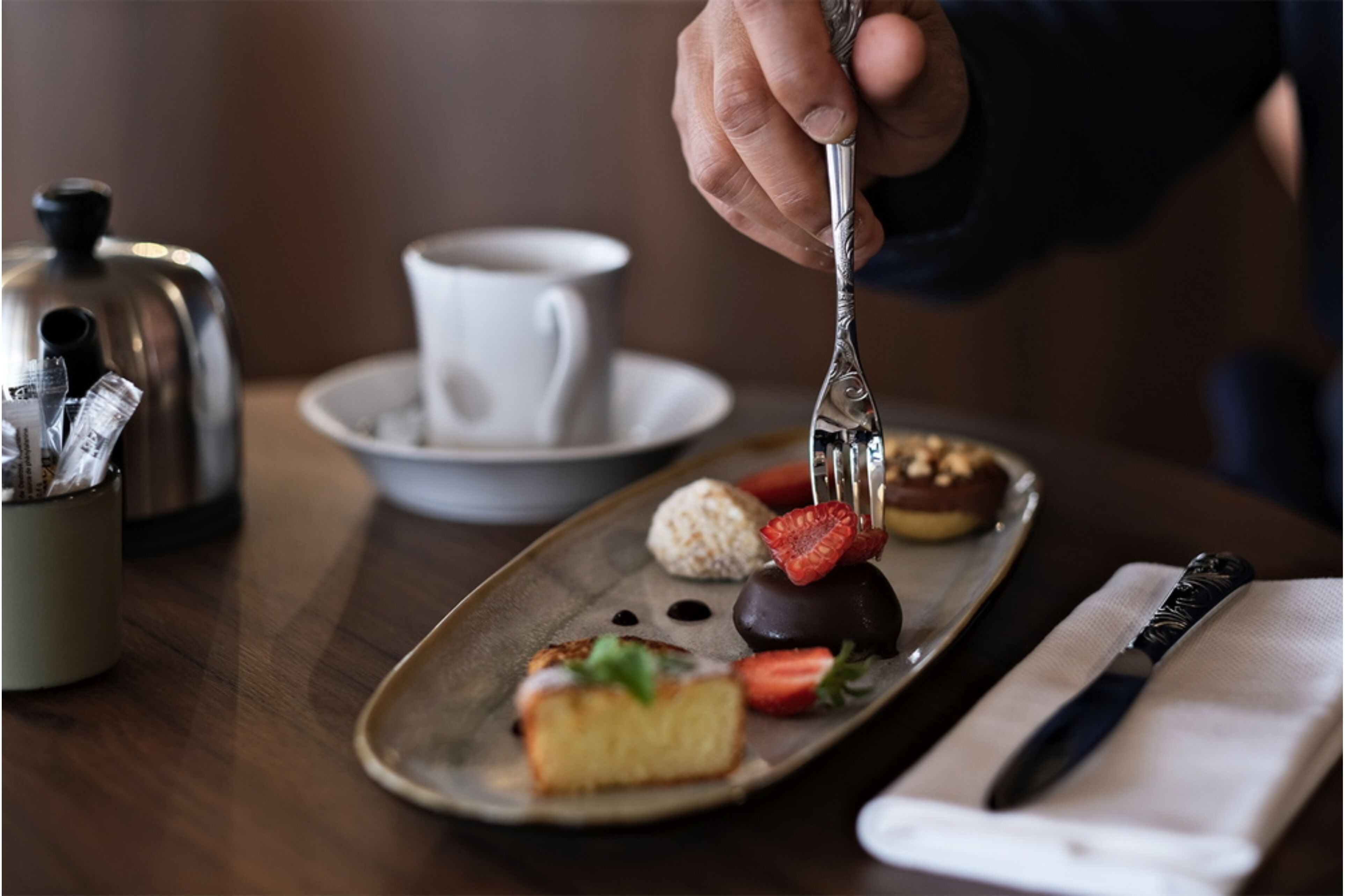 A tray with various desserts and a cup of coffee on a table.
