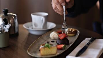 Una bandeja con diversos postres y una taza de café sobre una mesa.