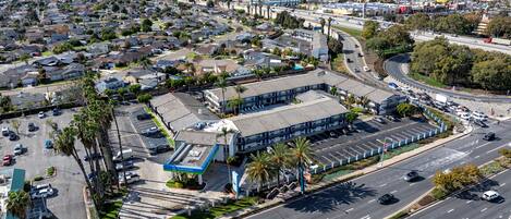 An aerial view of a hotel with a parking lot, multiple floors, and a surrounding urban area.