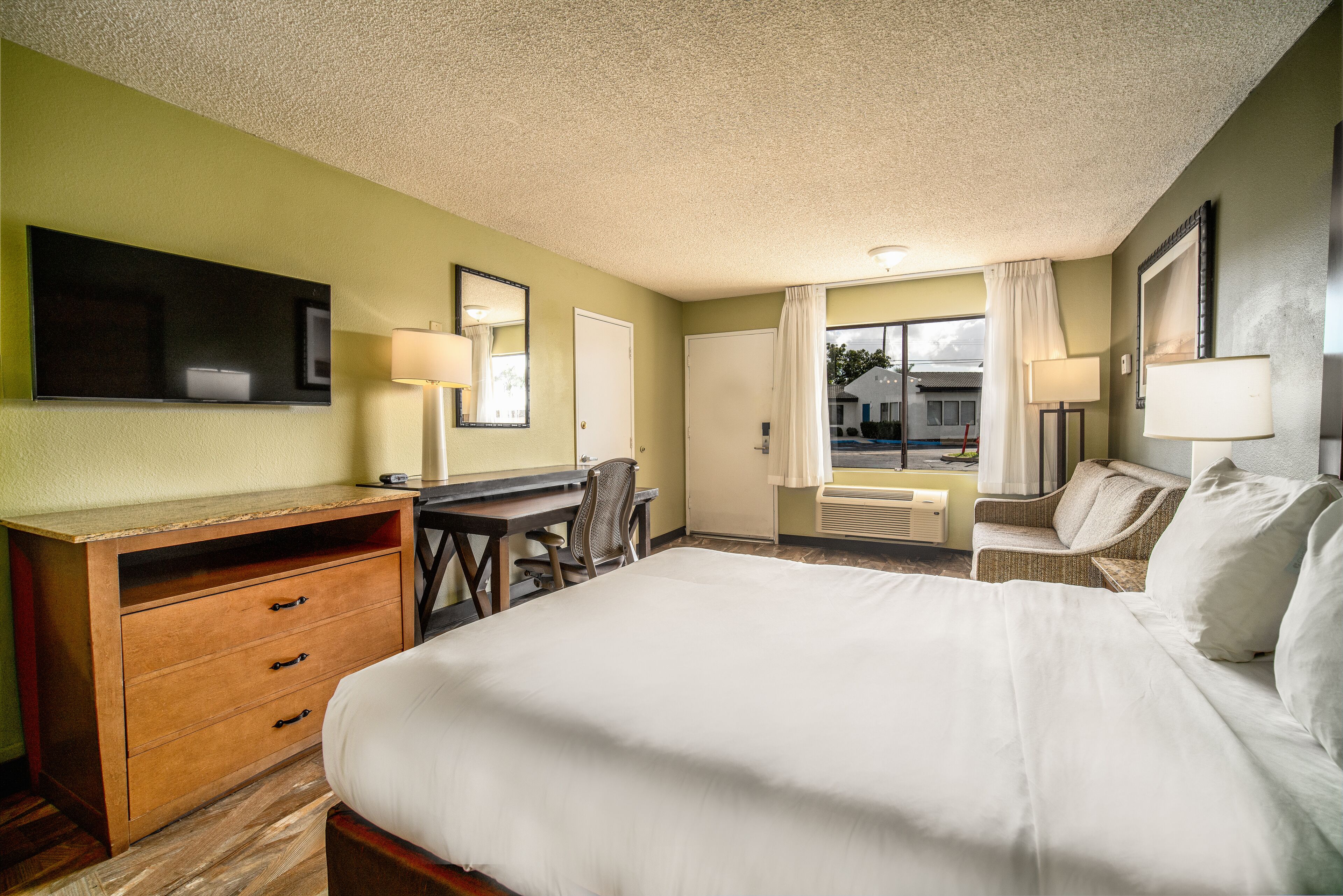 Quarto de hotel com cama grande, uma mesa, uma cadeira e televisão.
