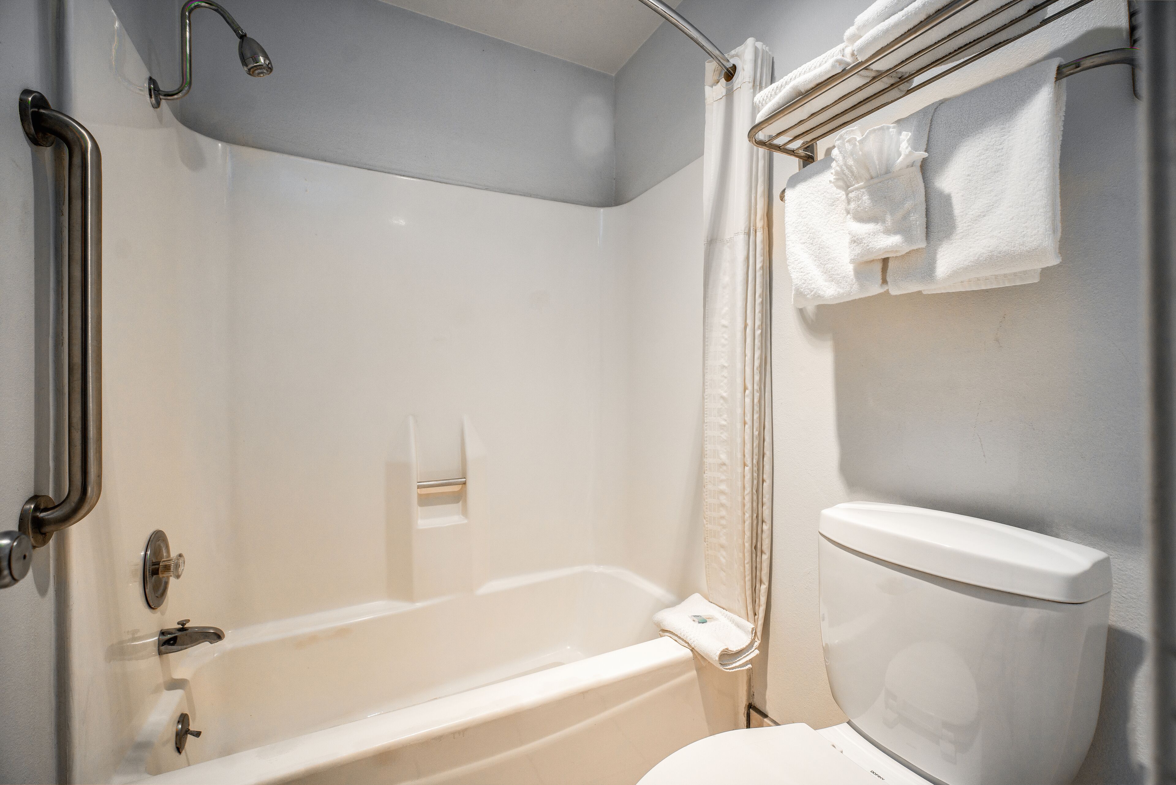 A bathroom with a bathtub, a toilet, and a shower area.