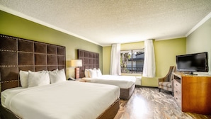 Habitación de hotel con dos camas, televisor, escritorio y ventana con cortinas.