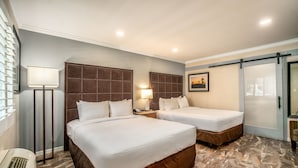 Habitación de hotel con dos camas, una lámpara de pie, un cuadro en la pared y una puerta corredera.