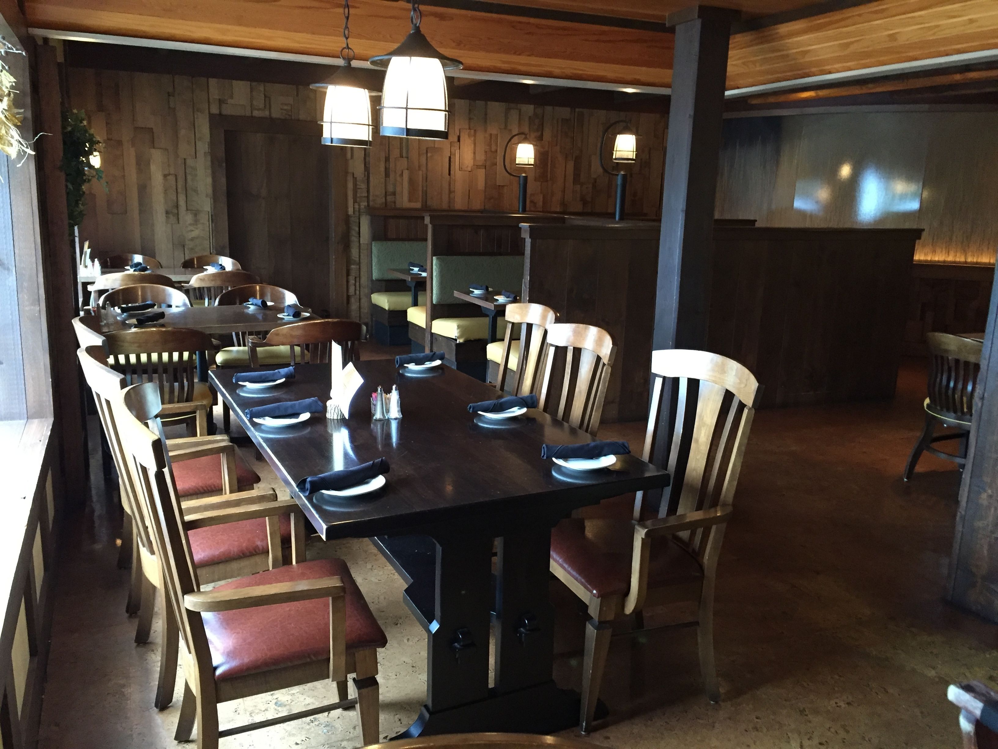 Un restaurante con una larga mesa de madera dispuesta para comer, rodeada de sillas de madera.