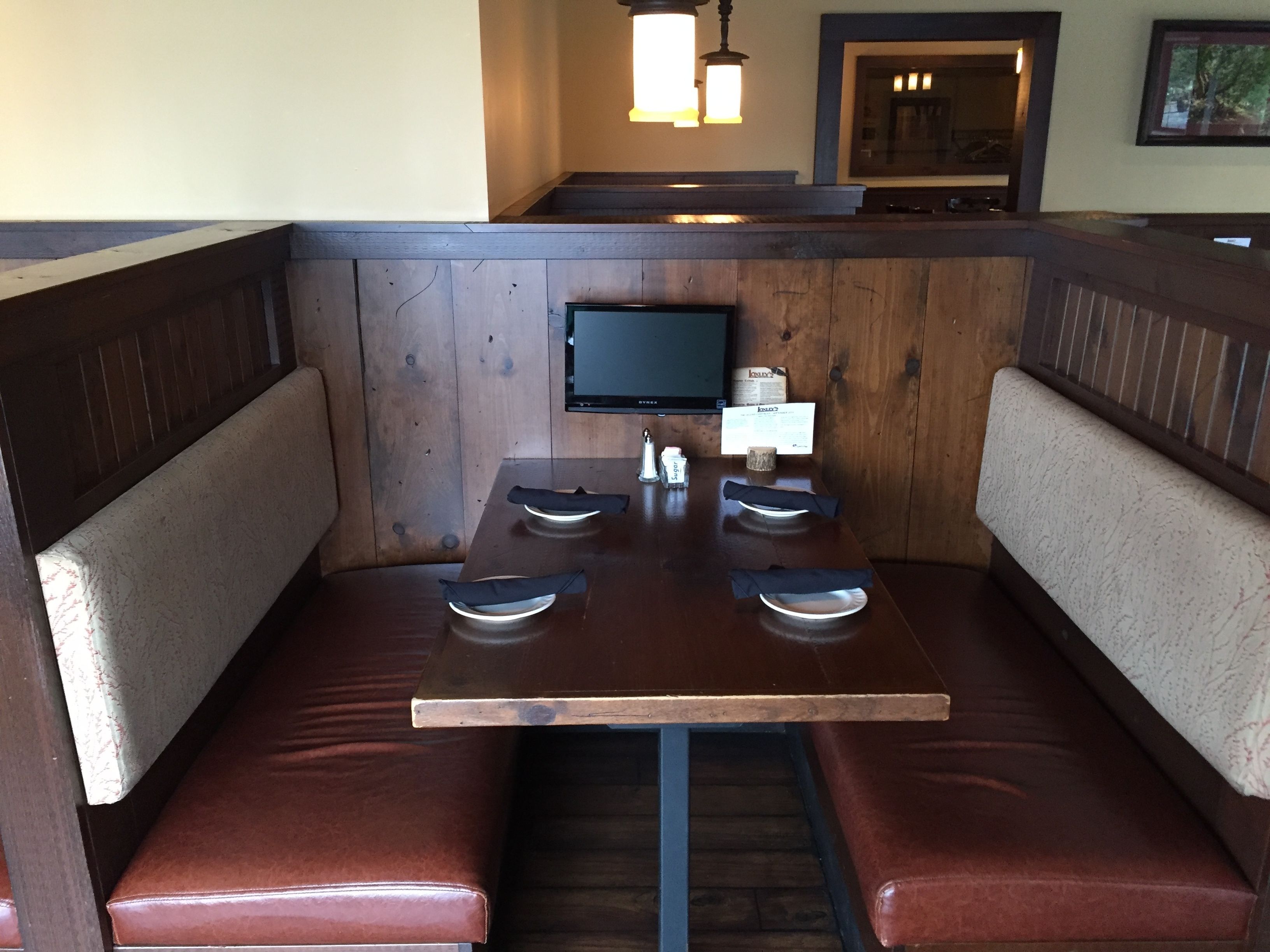 A restaurant booth with a wooden table and cushioned seats.
