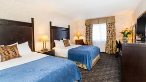 A hotel room with two beds, a television, a desk, and a window with curtains. - Heritage Hotel Lancaster (Lancaster)
