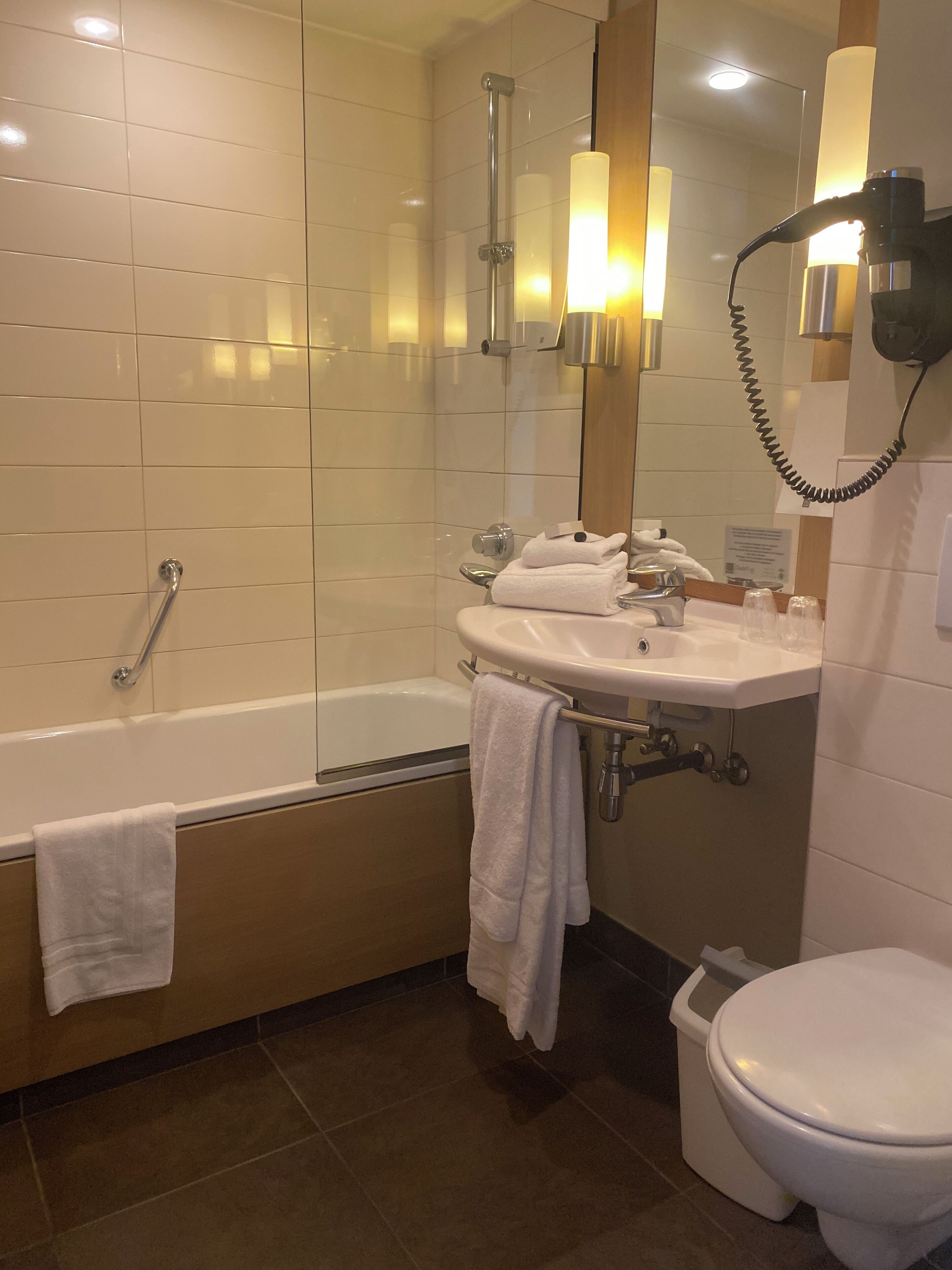 Un baño con bañera, lavamanos, inodoro y espejo.