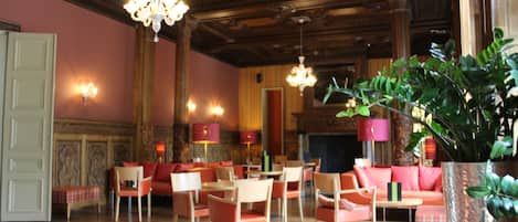 A spacious lobby with wooden flooring, multiple seating areas, and decorative chandeliers.