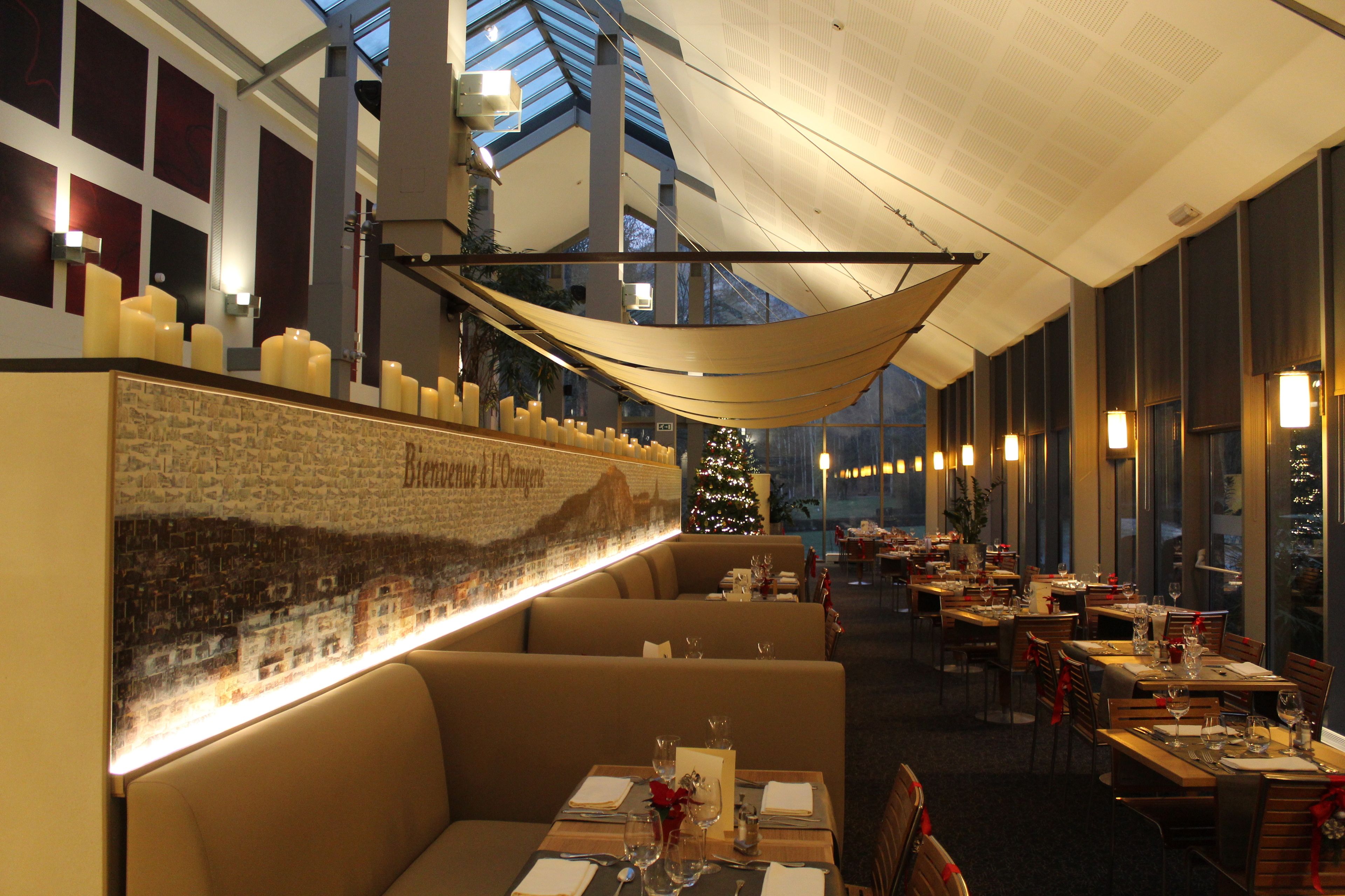 Een restaurant met hoge plafonds, grote ramen en een kerstboom.