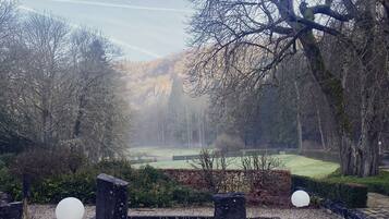 Un parque con un estanque, árboles y una vista distante de un campo de golf.