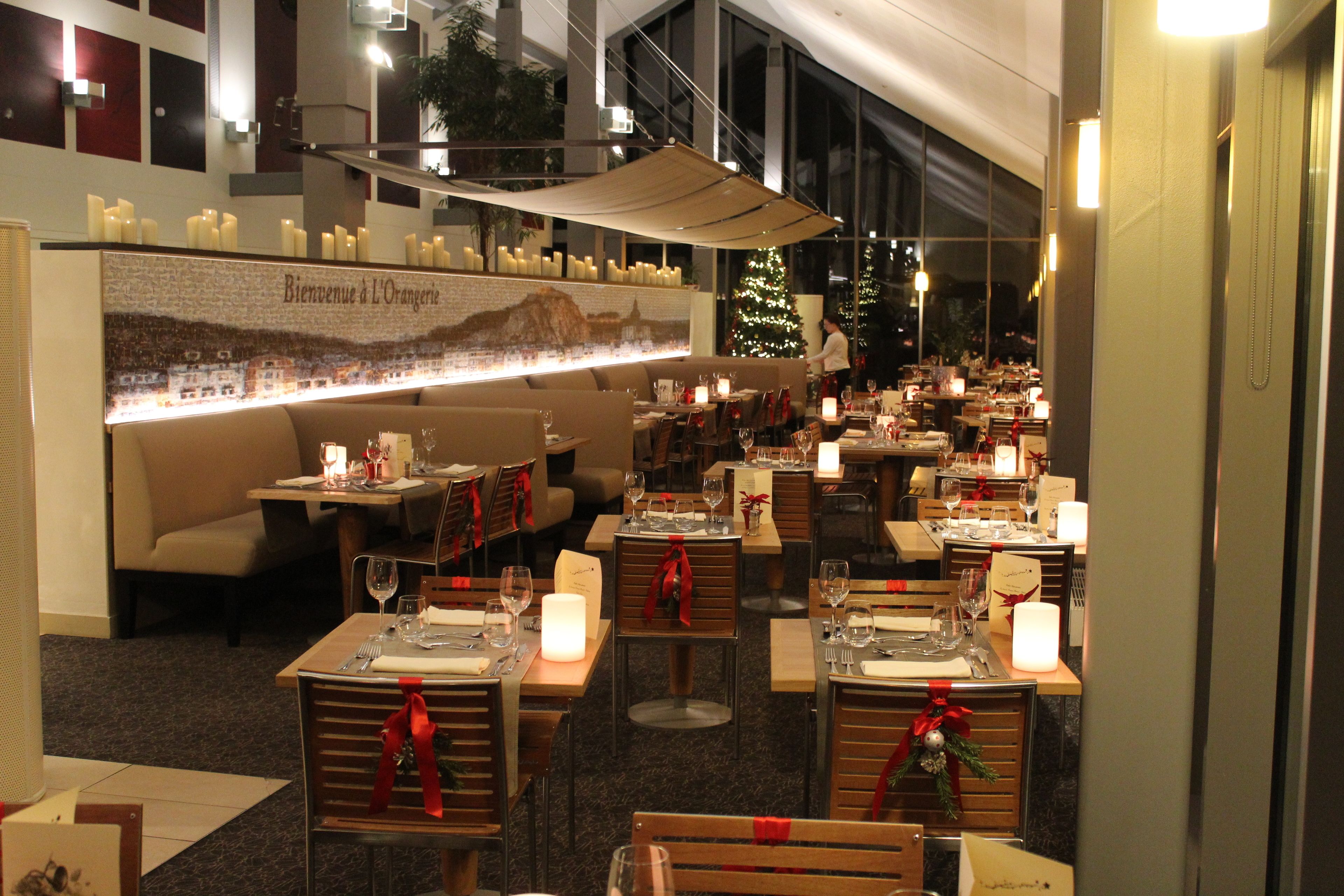 A restaurant with multiple tables and chairs, each set with candles and red ribbons.