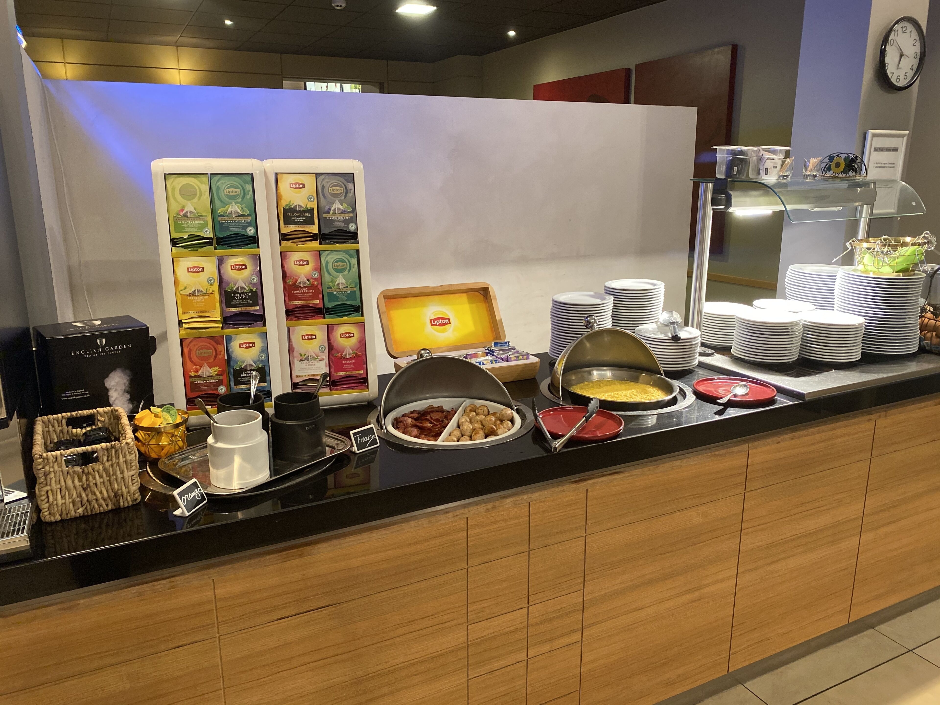 A buffet area with various food items, a coffee machine, and a selection of Lipton tea boxes.