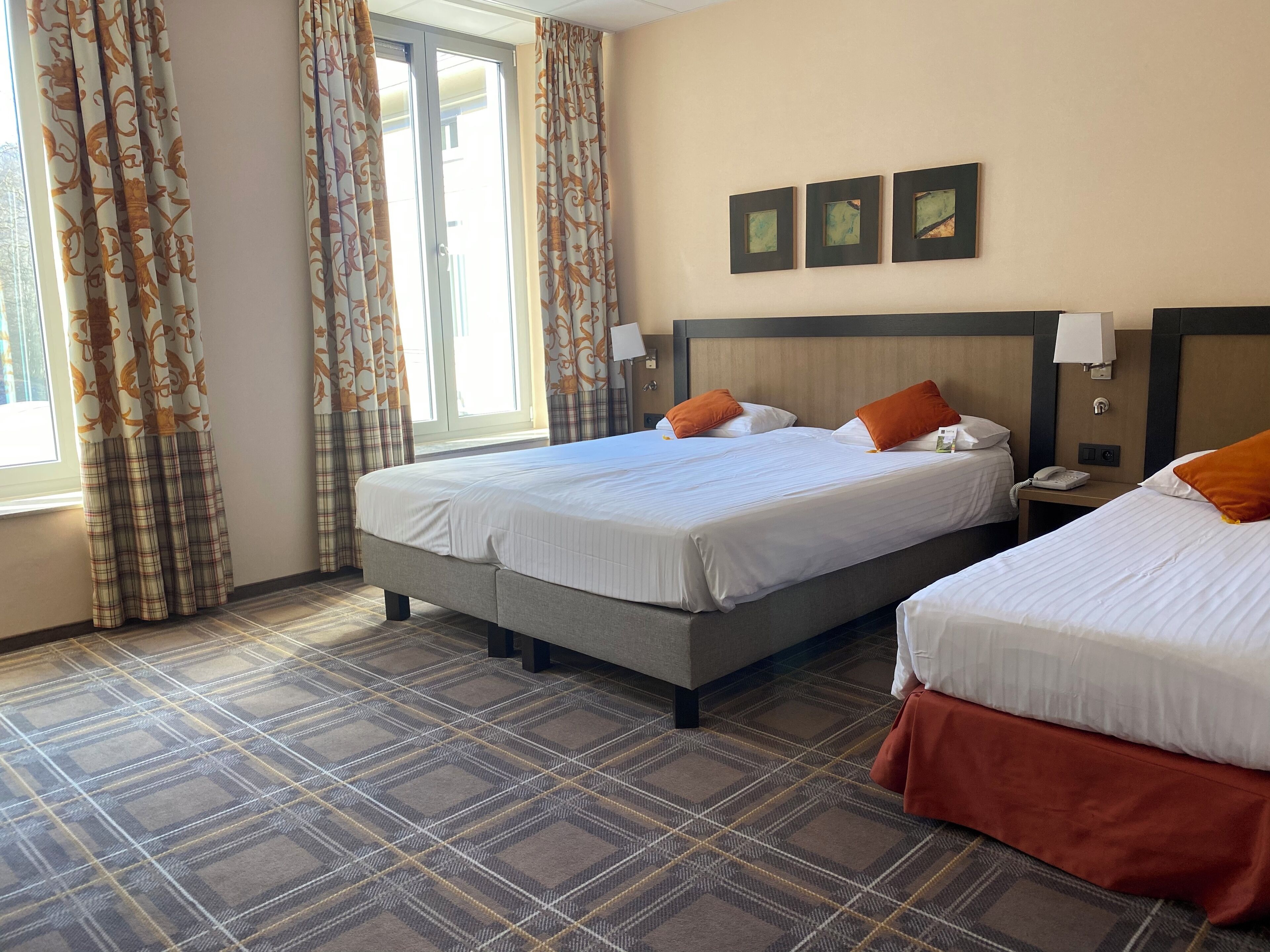 A hotel room with two beds, a check-in counter, and a window with curtains.