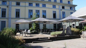 A building with outdoor seating and umbrellas. - Castel de Pont-à-Lesse Hotel (Dinant)