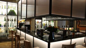 A bar area with a counter, stools, and shelves of bottles. - Castel de Pont-à-Lesse Hotel (Dinant)