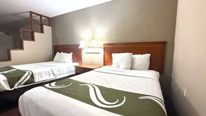 Two single beds with wooden headboards, a nightstand with a lamp, and a wall-mounted light fixture.