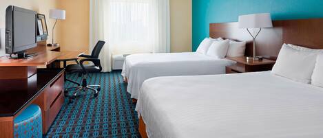 A hotel room with two beds, a desk with a computer, a chair, and a TV.