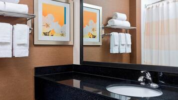 A bathroom with a black granite countertop, a white sink, and two framed floral artwork on the wall.
