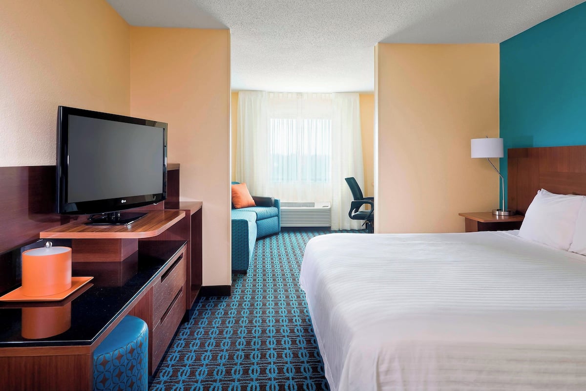 A hotel room with a bed, a TV, a desk, and a chair.