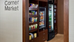 Une petite épicerie de quartier avec des étagères remplies d’en-cas et un réfrigérateur.