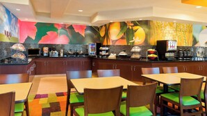 Un restaurant proposant un buffet, avec des chaises en bois dotées de coussins verts et un tapis aux couleurs vives.