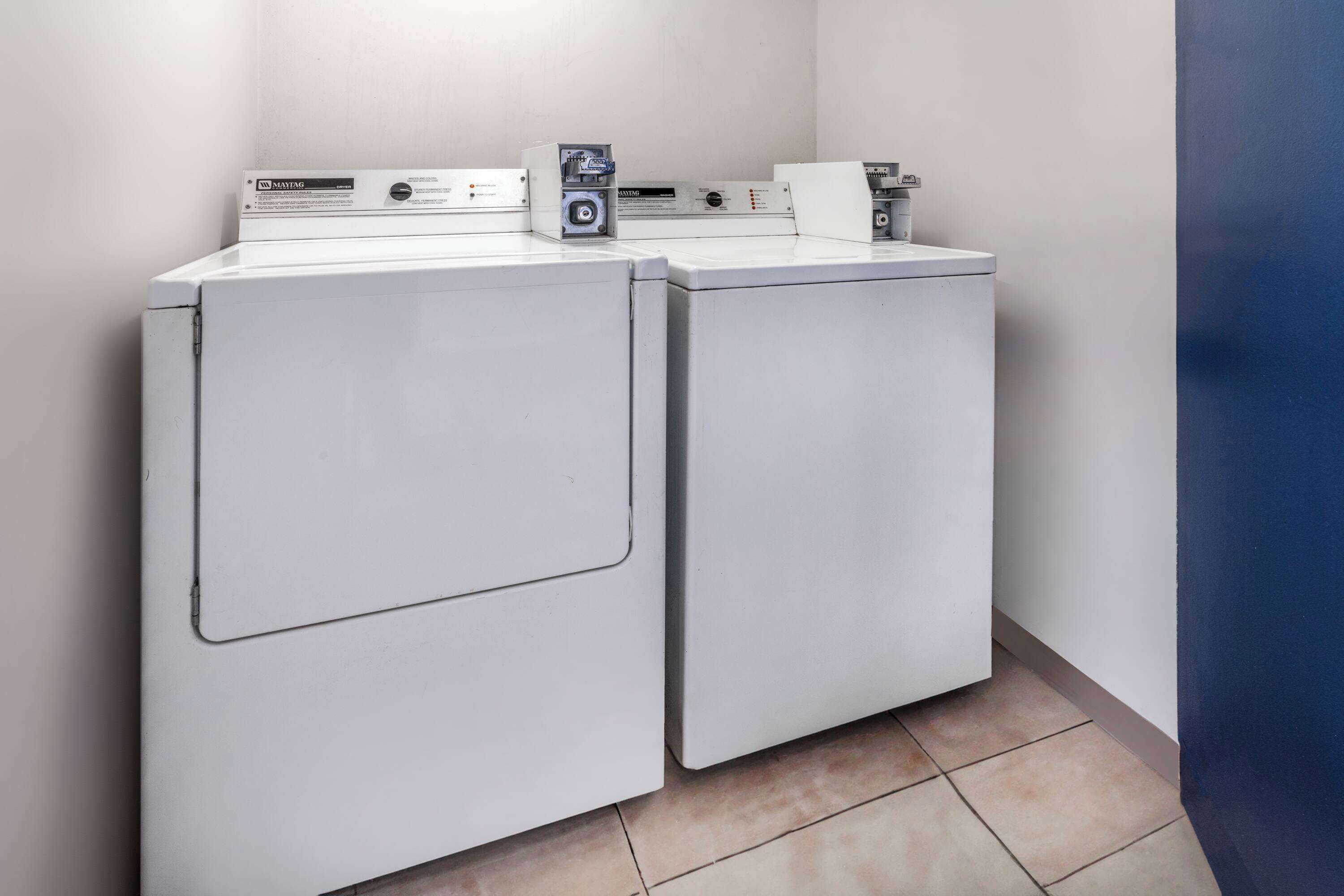 A laundry area with two front-loading washing machines and a dryer.