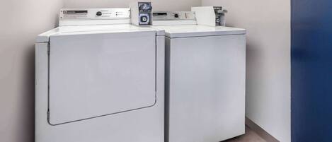 A laundry area with two front-loading washing machines and a dryer.