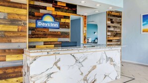 Un mostrador de recepción con el logotipo de Days Inn, una encimera de mármol y un panel de pared de madera.