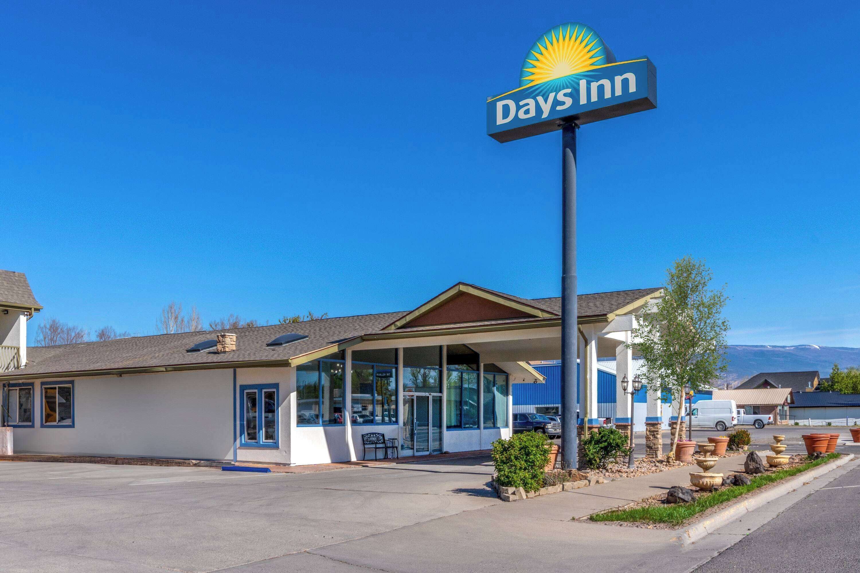 Een Days Inn hotel met een helderblauwe lucht, een groot bord en een parkeerplaats.